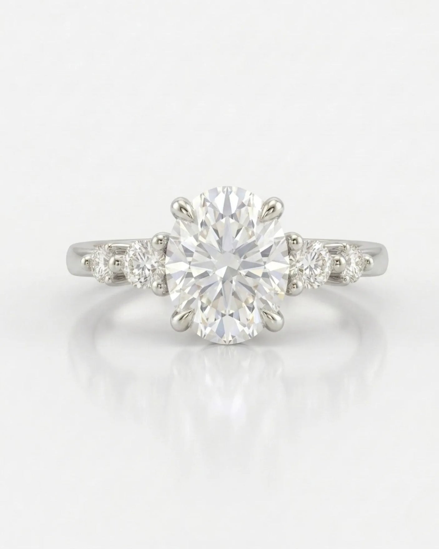 Sculptural oval diamond ring with flowing round side stones and high-polish 18K white gold band | SARATTI