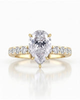Sculptural pear moissanite ring with hidden halo and accented shoulders in polished 18K yellow gold | SARATTI