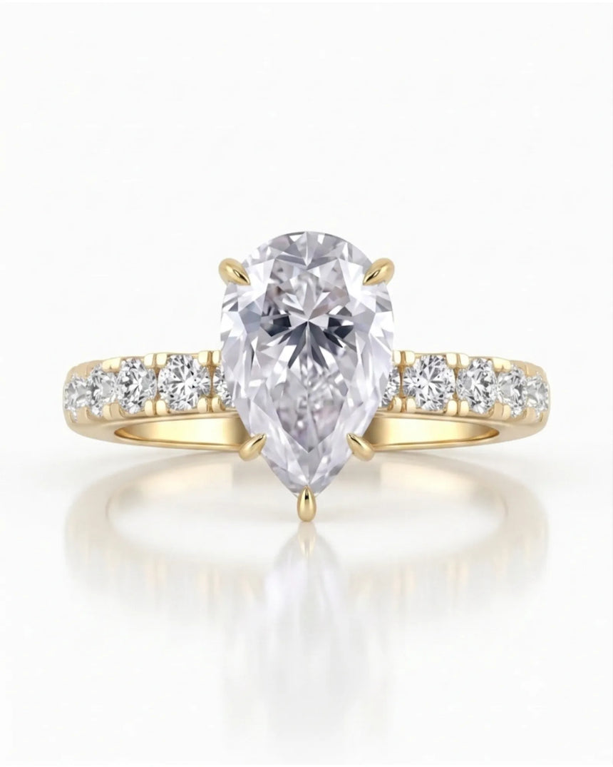 Sculptural pear moissanite ring with hidden halo and accented shoulders in polished 18K yellow gold | SARATTI