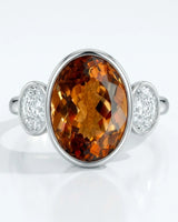 Smooth bezel setting frames the Imperial Topaz in a secure oval form in white gold | SARATTI