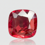 Square-cut red gemstone on a reflective surface with a light gray background