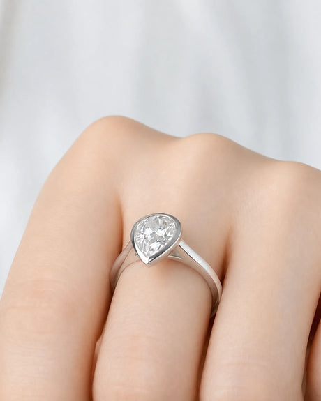 Aurelia's Embrace 1 carat pear-cut natural diamond bezel engagement ring in 18K white gold, worn on hand | SARATTI