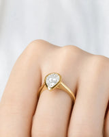 Aurelia's Embrace 1 carat pear-cut natural diamond bezel engagement ring in 18K yellow gold, worn on hand | SARATTI