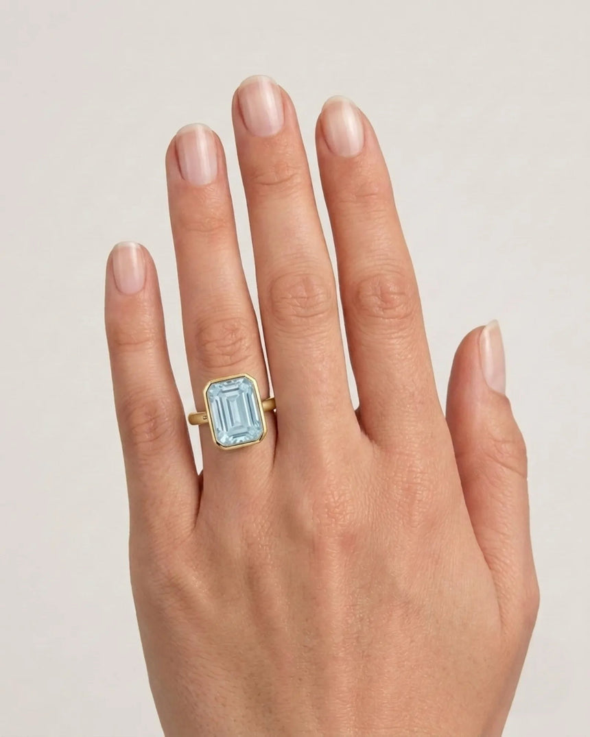 AUREX emerald cut Aquamarine bezel ring setting in Yellow Gold, shown on hand | SARATTI