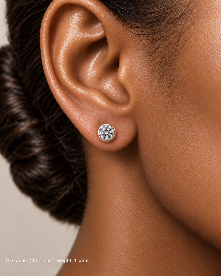 1.00 ct. tw. lab-grown round diamond full-bezel studs in 14K rose gold on deep skin | SARATTI