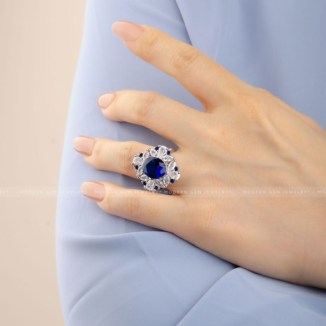 Oval Royal Blue Cocktail Ring with Sapphire and Diamond Accent Stones in 18K White Gold On Woman's Finger Close-Up Shot | Saratti